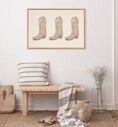 a wooden bench sitting next to a white wall with three pairs of boots on it