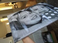 a person holding up a large poster with two girls on it