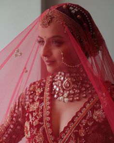 a woman wearing a red bridal gown and jewelry