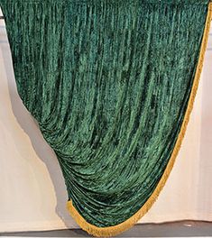 a green curtain hanging from the side of a white wall