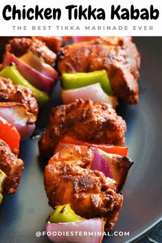 chicken tikka kabab on a black plate with red onions and green peppers