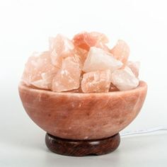 a wooden bowl filled with crystals on top of a white table next to a wire