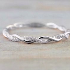 a white gold wedding band with diamonds on the sides and an elegant twist design in the middle