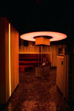 a dimly lit room with wooden walls and red lighting on the ceiling, along with benches