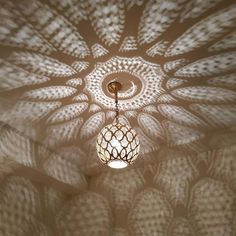 a light fixture hanging from the ceiling in a room with intricate designs on it's walls