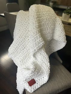 a white crocheted blanket sitting on top of a chair