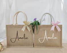 two bags with bows and name on them sitting next to each other in front of a white curtain