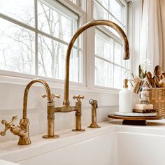 two faucets in a kitchen sink next to a basket with bread and flowers