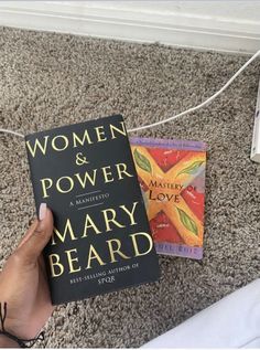 a person holding a book in their hand on the floor next to a string that reads women and power