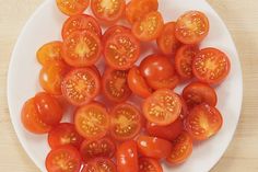 a white plate topped with sliced tomatoes on top of a wooden table