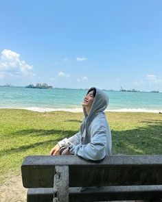 a man sitting on top of a cement bench next to the ocean with his eyes closed