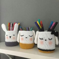 three crocheted mugs with pens and pencils in them sitting on a table