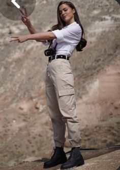 a woman in white shirt and khaki pants pointing at something