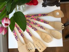 wooden utensils are lined up on a cutting board with flowers in the background