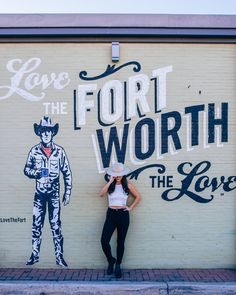 a woman standing in front of a wall painted with the words love and the furt worth