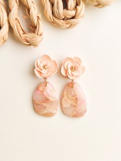 the pink flower earrings are on display next to some braided up hair and other items