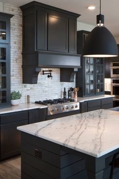 a kitchen with marble counter tops and black cabinets