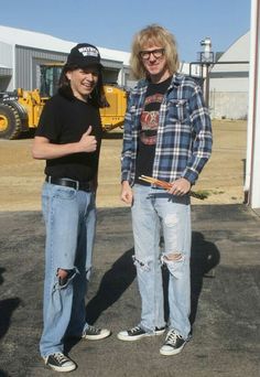 two young men standing next to each other in front of a construction site with machinery behind them