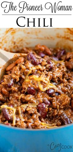 a blue pot filled with chili and beans next to a wooden spoon in the bowl