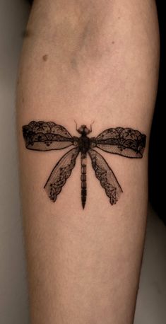 a black and white photo of a dragonfly tattoo on the right thigh, it's wings spread out