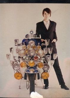 a man standing next to a motorcycle with lots of glasses on it's back