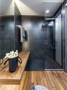 a modern bathroom with wood flooring and black walls, along with a large shower