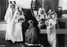 an old black and white photo of people dressed in traditional arabic garb sitting on a couch