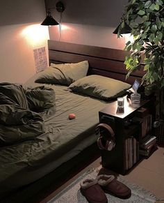 an unmade bed in a bedroom next to a night stand and lamp on the wall