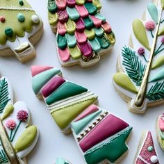 christmas cookies decorated with colorful icing on a white table top, including trees and pine cones