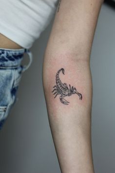 a woman's arm with a scorpion tattoo on the left side of her arm