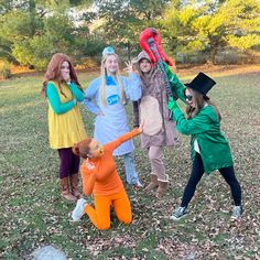 four girls in costumes are posing for the camera with one girl holding up her hands