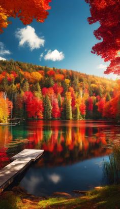 a lake surrounded by fall colored trees with a dock in the foreground and clouds in the background