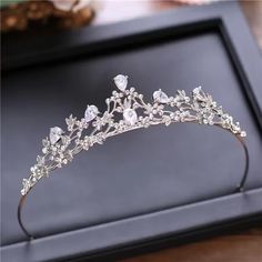 a tiara with crystal stones and leaves on the headpiece is shown in front of a black box