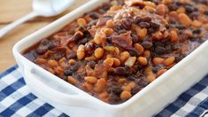 a white dish filled with beans on top of a blue and white checkered table cloth