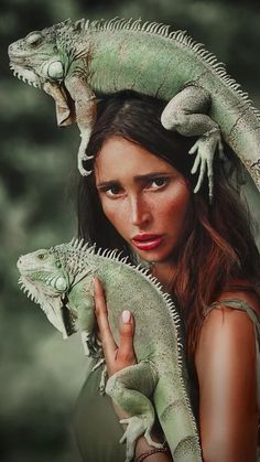 a woman is holding two green lizards on her head and the other one has it's face open