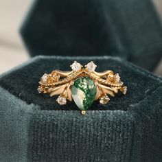 a close up of a ring with a green stone in the middle and diamonds on it