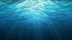 an underwater view of blue water with sunlight shining through the water