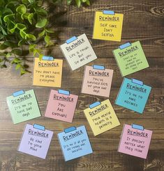 several sticky notes with reminders attached to them on a table next to a plant