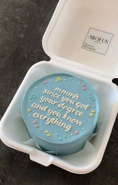 a blue cake in a plastic container with writing on the side and stars around it