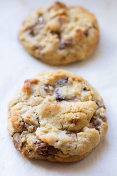 two chocolate chip cookies sitting on top of white paper