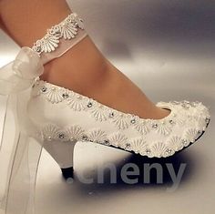 a woman's white high heeled wedding shoes with bows and beaded details