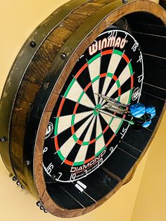 a dart board mounted to the side of a wooden barrel with darts stuck in it