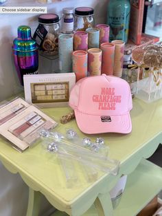 a pink hat sitting on top of a table next to bottles and other items in front of it