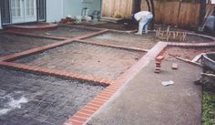 a man is working in the backyard with bricks on the ground and concrete around him