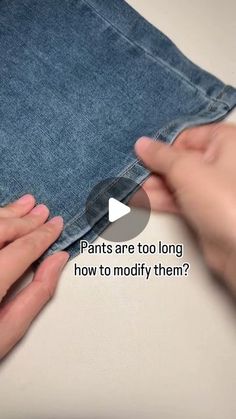 two hands are holding the bottom part of a pair of jeans, which is being folded