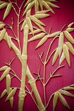 a bamboo plant is shown on a red background with gold leaves and stems in the foreground