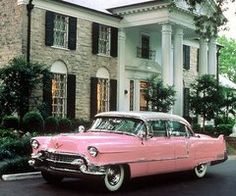 an old pink car parked in front of a large house