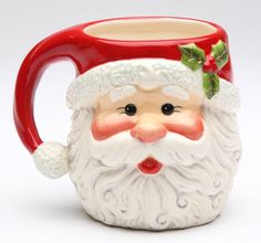 a ceramic santa claus mug with holly berry on the top and nose is sitting in front of a white background