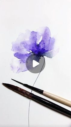 two pens are next to a purple flower on a piece of paper with watercolor pencils