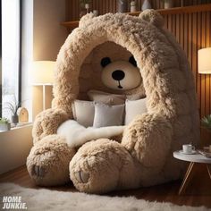 a large teddy bear sitting in a chair with pillows on it's feet and arms